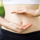 Close-up-young-womans-hands-slim-belly_1262-3479